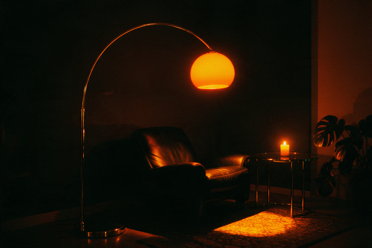 Chrome arc floor lamp glowing over a leather lounge chair at night