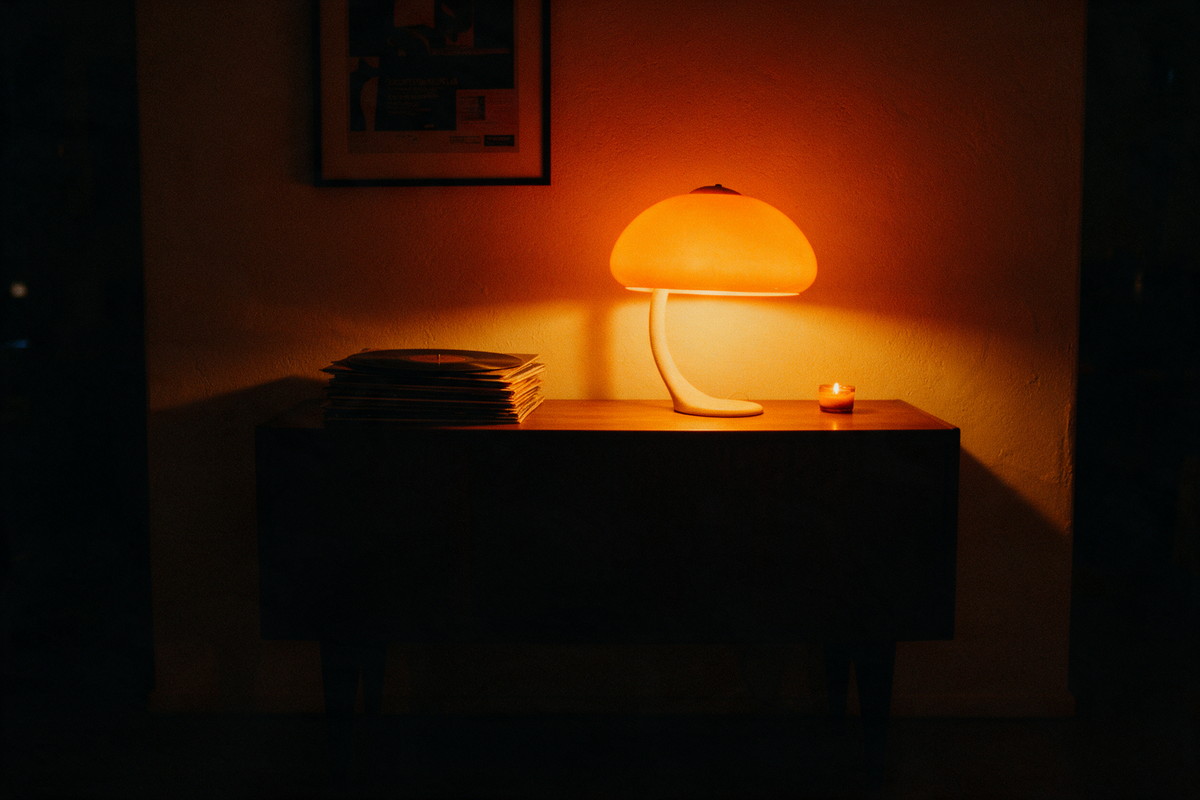 Mushroom table lamp glowing on a walnut console beside vinyl records